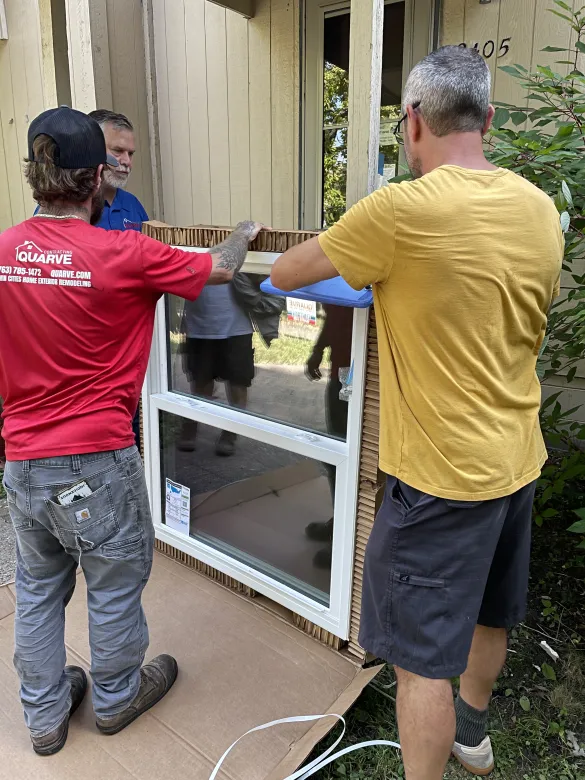 three people holding a window frame