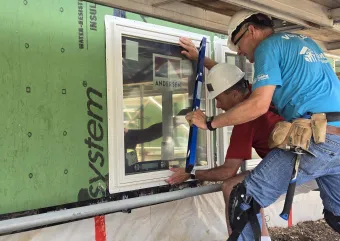 TC HFH volunteers installing triple-pane window